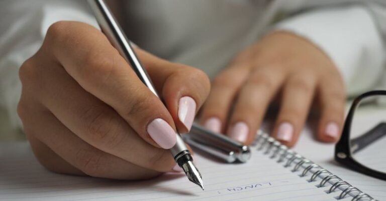 Hamster Schedule - Woman in White Long Sleeved Shirt Holding a Pen Writing on a Paper